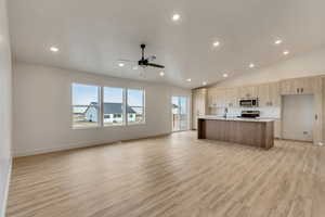 Kitchen with appliances with stainless steel finishes, ceiling fan, sink, light hardwood / wood-style flooring, and an island with sink