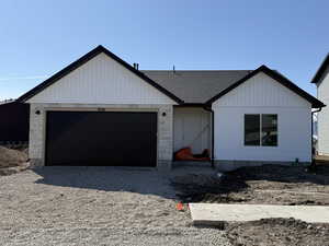 View of front of property with a garage and roof with shingles