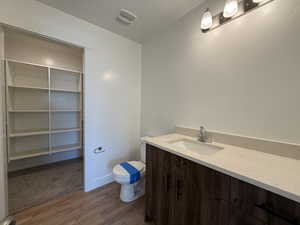 Bathroom with visible vents, toilet, a textured ceiling, wood finished floors, and vanity