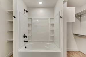 Bathroom with shower / bathing tub combination and hardwood / wood-style flooring