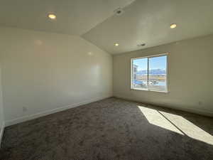 Carpeted empty room featuring visible vents, recessed lighting, baseboards, and vaulted ceiling