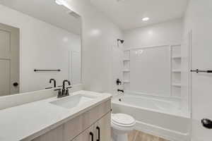 Full bathroom with hardwood / wood-style flooring, vanity, toilet, and bathing tub / shower combination