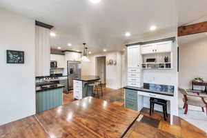 Kitchen featuring stainless steel appliances, a kitchen island, a kitchen breakfast bar, pendant lighting, and white cabinets