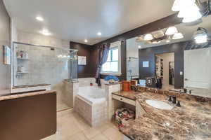 Bathroom featuring tile patterned flooring, vanity, and separate shower and tub