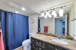 Bathroom with tile patterned flooring, a textured ceiling, vanity, and toilet