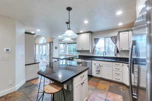 Kitchen with sink, white cabinets, a kitchen island, and appliances with stainless steel finishes