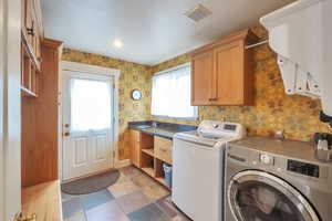 Clothes washing area with sink, cabinets, and independent washer and dryer