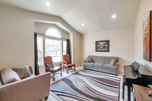 Carpeted living room featuring lofted ceiling