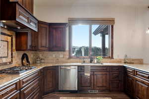 Kitchen featuring light stone countertops, appliances with stainless steel finishes, tasteful backsplash, and sink