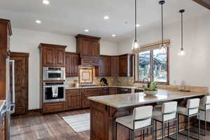 Kitchen featuring kitchen peninsula, backsplash, decorative light fixtures, and light stone counters