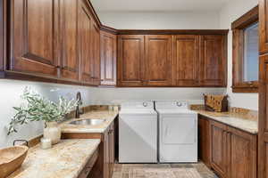 Laundry room featuring washing machine and dryer, sink, and cabinets