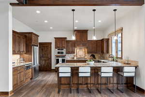 Kitchen featuring decorative backsplash, stainless steel appliances, sink, decorative light fixtures, and dark hardwood / wood-style floors