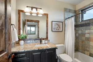 Full bathroom with shower / bath combo with shower curtain, vanity, and toilet