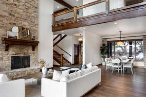 Living room with a fireplace, a towering ceiling, and dark wood-type flooring