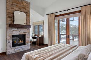 Bedroom featuring access to exterior, a stone fireplace, dark hardwood / wood-style flooring, a mountain view, and lofted ceiling