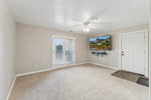 Large living room with ceiling fan, double doors that lead to the patio,  and brand new carpet floors!