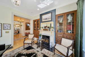 Sitting room with  a fireplace, wood flooring, and ornamental molding and orginal huge solid wood pocket doors.