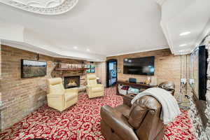 Living/Movie room with a brick fireplace, ornamental molding, and brick wall