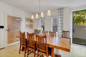 Dining room with light hardwood / wood-style floors and a notable chandelier