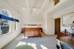 Bedroom with lofted ceiling with beams, light colored carpet, and loft