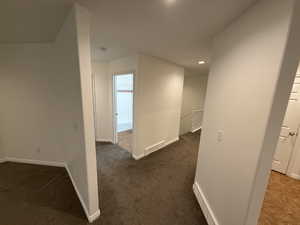 Hall featuring dark colored carpet