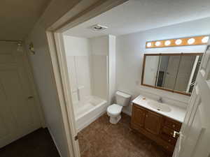 Full bathroom featuring vanity, a textured ceiling, toilet, and washtub / shower combination