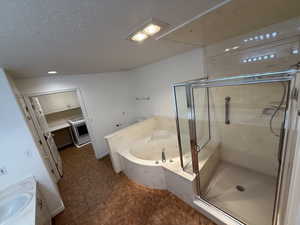 Bathroom featuring separate shower and tub, washer / clothes dryer, lofted ceiling, a textured ceiling, and vanity