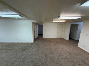 Empty room with carpet flooring and a textured ceiling