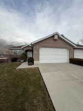 Ranch-style home with a mountain view, a garage, and a front lawn