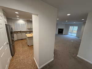 Kitchen featuring backsplash, sink, appliances with stainless steel finishes, light colored carpet, and white cabinetry