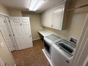 Laundry room featuring cabinets, separate washer and dryer, and a textured ceiling