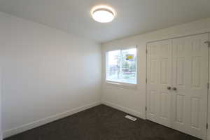 Unfurnished bedroom featuring dark colored carpet and a closet