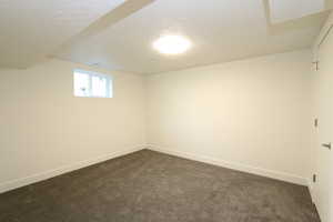 Spare room with a textured ceiling and dark carpet