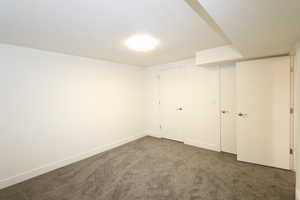 Unfurnished bedroom featuring dark carpet, a textured ceiling, and a closet