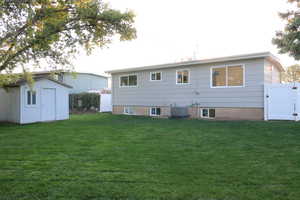 Rear view of property featuring a shed, a yard, and central air condition unit