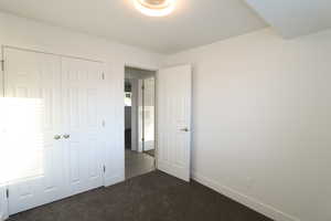 Unfurnished bedroom with dark carpet and a closet