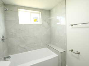 Bathroom featuring tiled shower / bath combo and toilet