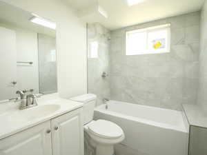 Full bathroom featuring tiled shower / bath, vanity, and toilet