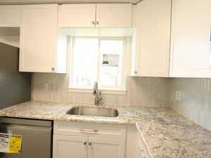 Kitchen with sink, white cabinetry, tasteful backsplash, and dishwasher