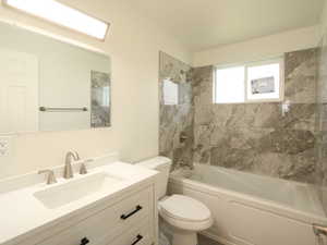 Full bathroom with toilet, tiled shower / bath, and vanity