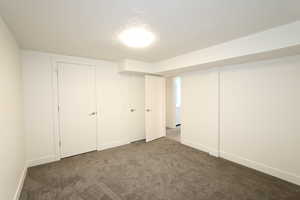 Basement featuring dark carpet and a textured ceiling