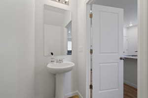 Half Bathroom with hardwood / wood-style floors and sink