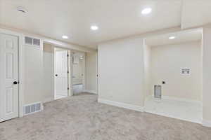 Interior space with hookup for a washing machine, light colored carpet, and electric dryer hookup