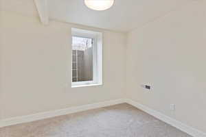 Empty room with carpet and beam ceiling