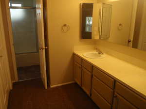 Bathroom featuring vanity and bath / shower combo with glass door