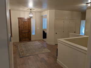 Entryway with dark wood-type flooring, a chandelier, and a textured ceiling