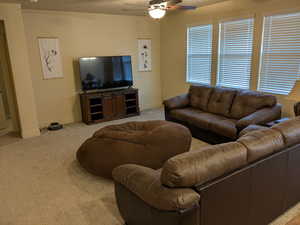 Carpeted living room with ceiling fan