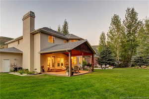 Back of house featuring a lawn and a patio area