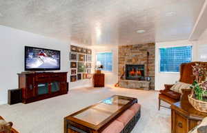 Carpeted living room with a textured ceiling and a stone fireplace