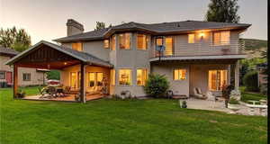 Back house at dusk featuring a balcony, a yard, and a patio